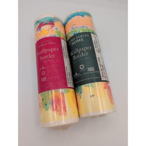 May include: Two rolls of Laura Ashley Home matt vinyl wallpaper border. The left roll has a magenta label, and the right roll has a dark green label. Each roll is 10m long and 178 mm wide, featuring a colorful, abstract painted pattern.