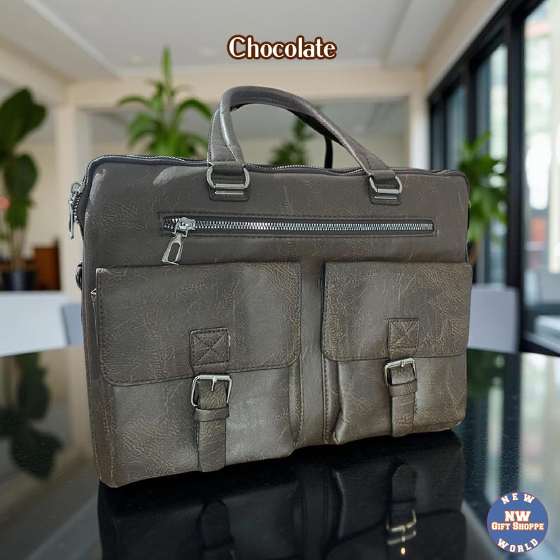 A dark brown vegan leather briefcase with two front buckled pockets, a top zipper, and two handles, rests on a black reflective surface.