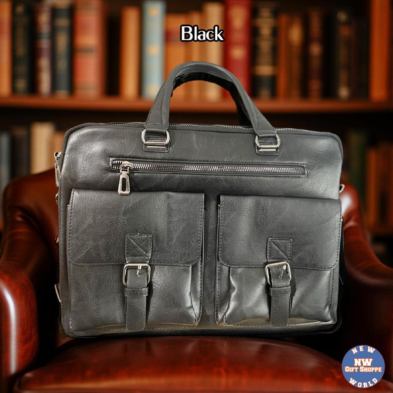 A black vegan leather briefcase with two front buckled pockets, a top zipper, and two handles, rests on a brown leather chair.