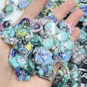 May include: A large collection of colourful, translucent, anime-style character charms. The charms are made of clear plastic with printed designs and are in various shapes and sizes.