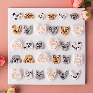 Könnte beinhalten: Eine weiße Silikon-Backform mit 24 verschiedenen Designs in Hundeform. Die Form befindet sich auf einem weißen Hintergrund.