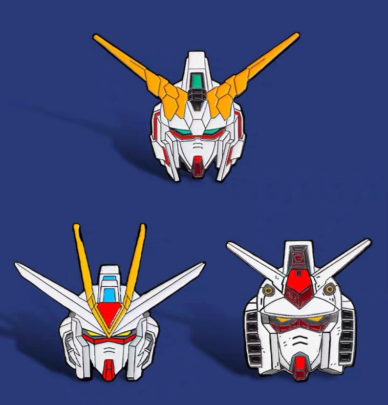 May include: Four enamel pins featuring the heads of different robots from the anime series Gundam. The pins are white, red, and yellow with black outlines.