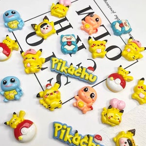 以下が含まれることがあります： ピカチュウ、ゼニガメ、その他のポケモンキャラクターをフィーチャーした、カラフルな漫画キャラクターチャームの詰め合わせ。チャームはレジン製で、光沢のある仕上げになっています。