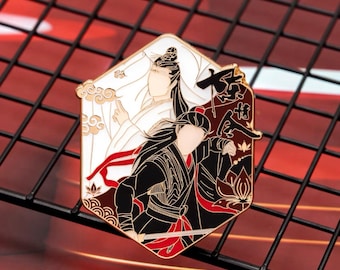 May include: A gold-toned enamel pin depicting two figures, one in a white robe and the other in black clothing. The pin has a red and gold background with Chinese characters and lotus flowers.