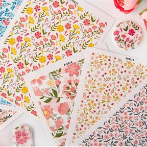 May include: Four sheets of floral patterned nail stickers. The stickers feature different floral designs in pink, yellow, and green. The sheets are labelled with the product codes PY0013, PY0014, and PY0015.