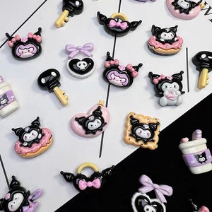 May include: Assortment of black and white cartoon character charms with pink, purple, and yellow accents. The charms feature a variety of designs, including hearts, donuts, keys, and coffee cups.