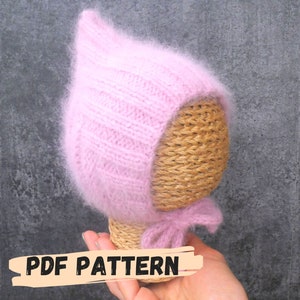 May include: A pink knitted baby bonnet with a fluffy texture. The bonnet is on a mannequin head and has a bow tied at the bottom. The text "PDF PATTERN" is visible at the bottom of the image.