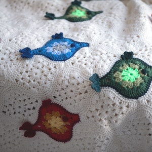 Puede incluir: Una manta blanca de ganchillo con aplicaciones de peces de colores. Los peces est&aacute;n hechos con hilo de diferentes colores y tienen una variedad de dise&ntilde;os.
