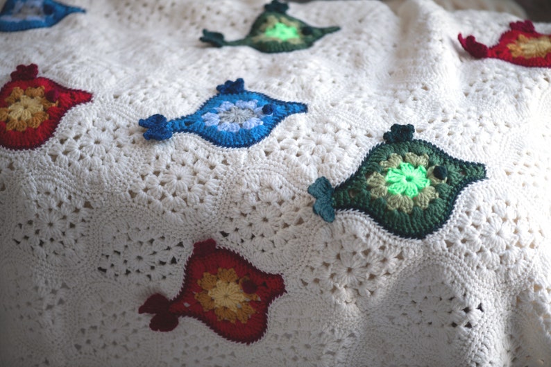Puede incluir: Una manta blanca de ganchillo con aplicaciones de peces de colores. Los peces est&aacute;n hechos con hilo de diferentes colores y tienen una variedad de dise&ntilde;os.