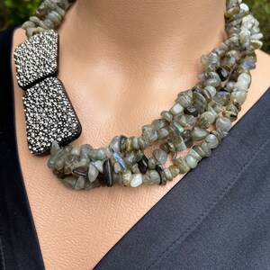 May include: A multi-strand necklace made of grey and green gemstone beads with a silver rhinestone accent.