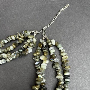 May include: A multi-strand necklace made of grey and green labradorite stones. The necklace has a silver chain extender.