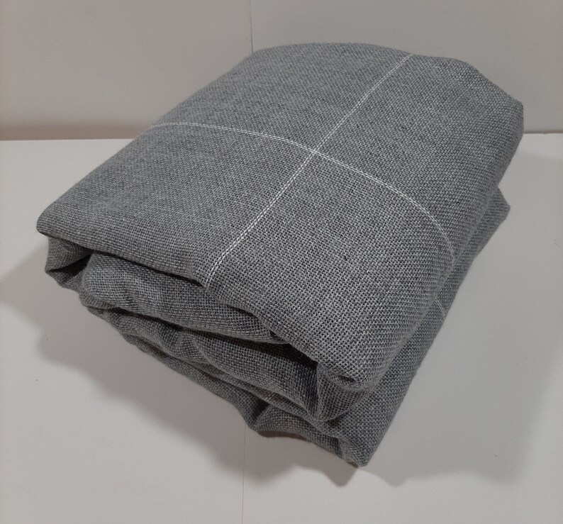 May include: Folded gray fabric with a white grid pattern. The fabric is a medium gray color and appears to be a woven material. The grid lines are thin and evenly spaced, creating a subtle design.