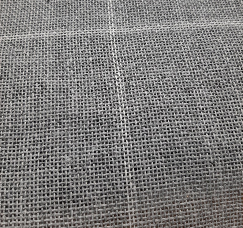 May include: Close-up of a gray woven fabric with a fine, even texture. The fabric has a subtle sheen and appears to be made of natural fibers.