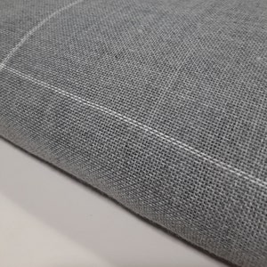 May include: Close-up of a gray fabric with a woven texture. The fabric has a subtle white grid pattern running across it. The material appears to be soft and could be used for clothing or home decor.