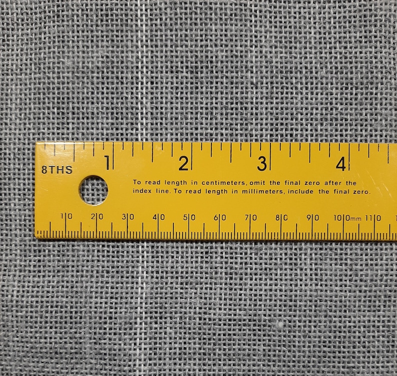 May include: A yellow ruler with black markings and the text "8THS" and "To read length in centimeters, omit the final zero after the index line. To read length in millimeters, include the final zero." The ruler is marked in centimeters and millimeters from 1 to 4.