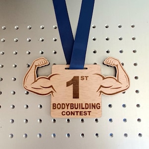 May include: Wooden first place award with a muscular arm design and the text "1st BODYBUILDING CONTEST".