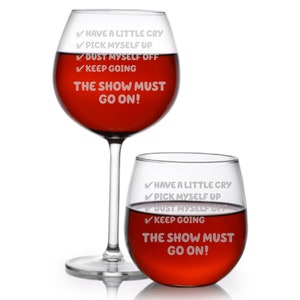 May include: Two wine glasses with red wine. The glasses are engraved with the text "✓ HAVE A LITTLE CRY ✓ PICK MYSELF UP ✓ DUST MYSELF OFF ✓ KEEP GOING THE SHOW MUST GO ON!"