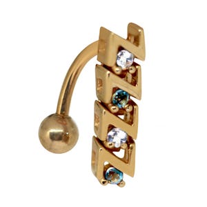 Puede incluir: Anillo de ombligo de oro con una barra curva y un dije decorativo con un diseño en zigzag con piedras preciosas transparentes y azules.