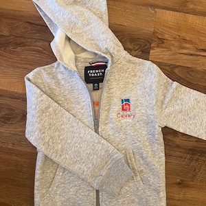 May include: Gray zip-up hoodie with a French Toast logo and a Calvary logo with a building graphic.