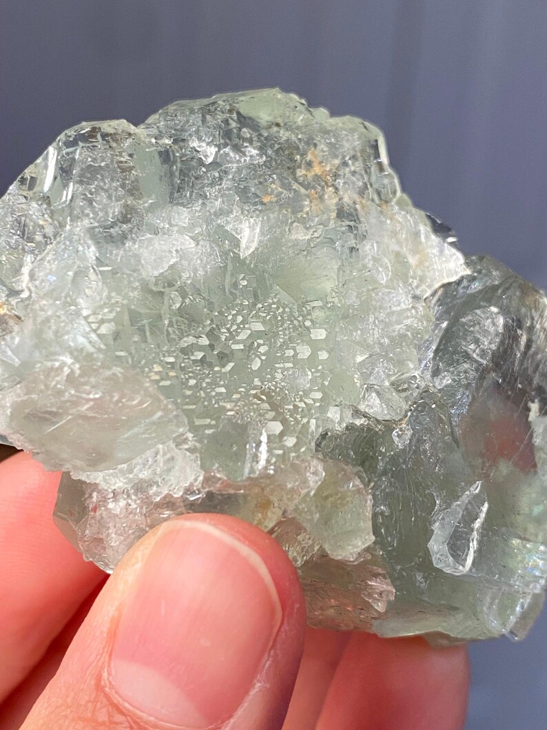 Puede incluir: Un racimo de cristales de fluorita verde p&aacute;lido, crudo y transl&uacute;cido, con facetas geom&eacute;tricas angulares y afiladas y una textura cristalina v&iacute;trea. El esp&eacute;cimen mineral muestra inclusiones internas y niveles variables de claridad en su estructura.