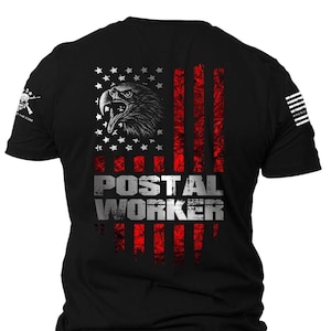 May include: Black t-shirt with a red, white, and blue American flag design. The flag has a bald eagle in the upper left corner and the words "POSTAL WORKER" in white letters below the flag.