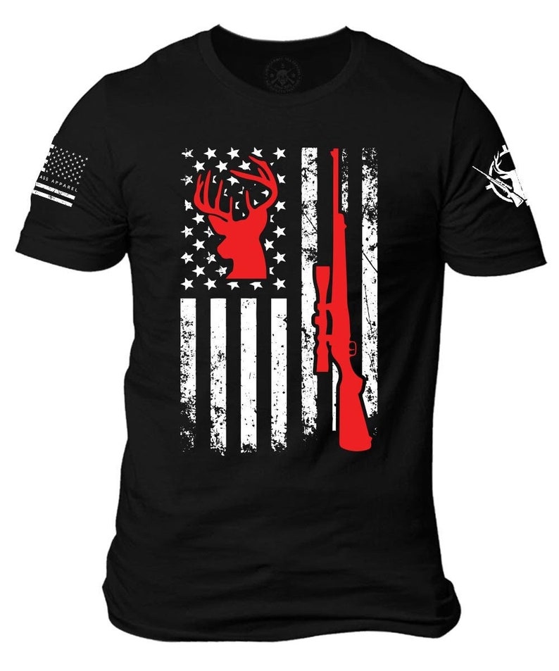 May include: Black t-shirt featuring a distressed American flag design. The flag incorporates a red deer silhouette and a rifle. The left sleeve displays a small American flag, and the right sleeve has a white hunting-themed graphic.