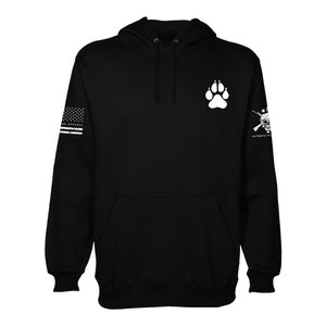 May include: Black hooded sweatshirt with a white paw print on the front and a white American flag and skull graphic on the sleeves. The text "PATRIOTIC TO THE CORE" is on the right sleeve.