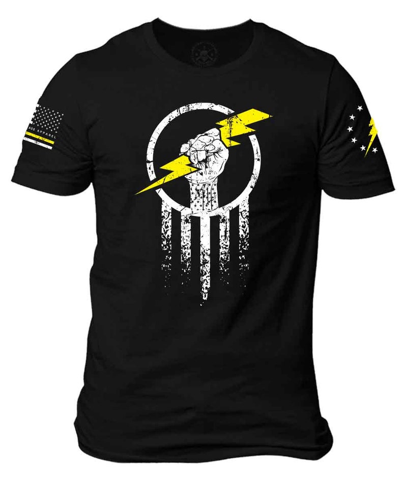 K&ouml;nnte beinhalten: Schwarzes T-Shirt mit einer wei&szlig;en und gelben Grafik einer Faust, die einen Blitz in einem Kreis h&auml;lt. Die Grafik ist auf eine wei&szlig;-schwarze amerikanische Flagge gelegt.