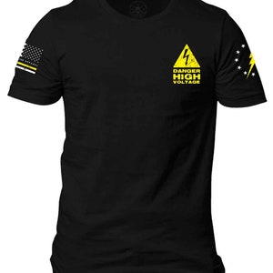 May include: Black t-shirt with a yellow warning sign that says "Danger High Voltage" and a lightning bolt. The shirt has American flag patches on the sleeves.