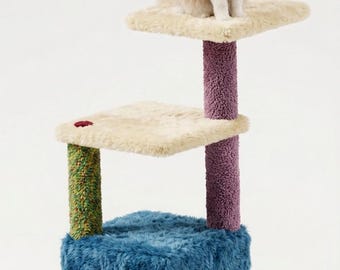 May include: A multi-level cat tree featuring a blue fuzzy base cube with a hollow entrance, a green textured scratching post, a purple textured scratching post, and two cream-coloured plush platforms. A cream and orange cat sits on the top level.