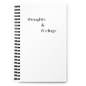 May include: A white spiral bound notebook with the text "thoughts & feelings" printed on the front cover.