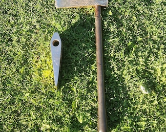 May include: Two metal tools, one with a wooden handle and a silver blade with a decorative pattern, and the other a silver blade with a pointed tip, on a green grassy surface.