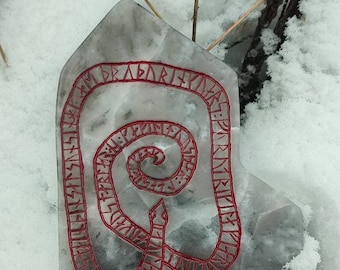 May include: A gray stone with a red snake design carved into it. The snake is curled up in a spiral shape and is surrounded by runes. The stone is sitting on a bed of snow.