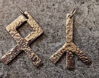 May include: Two silver-colored pendants with hammered textures. One pendant is a diamond shape with a square cut out, and the other is a three-pronged shape. Both have small loops for hanging.