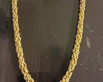 May include: A gold chain necklace with a byzantine style chain pattern.