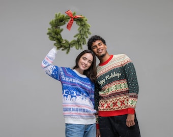 May include: Two long-sleeve knit sweaters featuring festive patterns. One sweater is blue and white with reindeer and snowflake motifs. The other is dark green with red and white geometric designs and the text Happy Holidays.