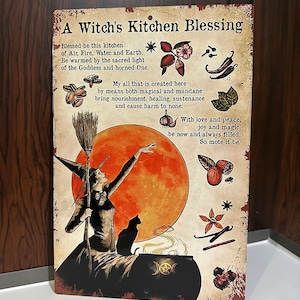 May include: A metal sign with a witch's kitchen blessing. The sign features a witch with a broom, a black cat, a cauldron, and a full moon. The text reads "A Witch's Kitchen Blessing. Blessed be this kitchen of Air, Fire, Water and Earth. "Be warmed by the sacred light of the Goddess and horned One. My all that is created here by means both magical and mundane bring nourishment, healing, sustenance and cause harm to none. With love and peace, joy and magic, be now and always filled. So mote it be."