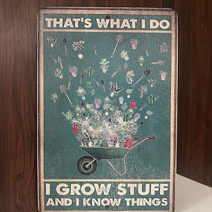 May include: A green metal sign with the text "That's what I do I grow stuff and I know things". The sign features a wheelbarrow overflowing with plants and gardening tools.