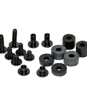 May include: An assortment of black hardware components, including screws, bolts, and cylindrical spacers. The fasteners vary in size and shape, with threaded shafts and flat or rounded heads. The spacers are ring-shaped with a central hole.
