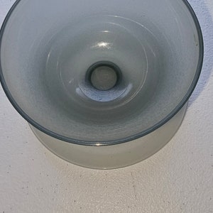 May include: A clear glass bowl with a wide rim and a slightly raised center. The bowl has a frosted finish and a smooth, rounded shape.
