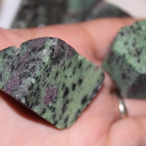 May include: Two green, black, and purple gemstone rocks. The rocks are irregularly shaped and have a rough, natural texture.