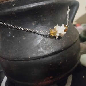 May include: A silver chain necklace with a white bone charm and two amber beads.