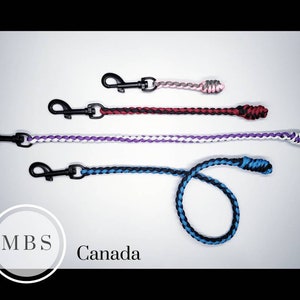 May include: Four different coloured braided dog leads with black metal clips. The leads are in the colours red, purple, blue, and grey.
