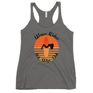 May include: Gray racerback tank top with a graphic featuring a sunset design with a surfboard and a silhouette of a person. The text reads "Wave Rider Hot Wife Club" in a stylized font.