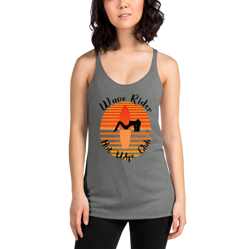 May include: Gray tank top with a scoop neck featuring a sunset graphic with a surfboard and a silhouette of a person. The text reads "Wave Rider Hot Wife Club" in a circular design.