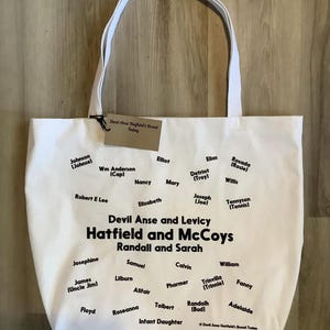 May include: White canvas tote bag with black text listing the names of the Hatfield and McCoy families. The text reads "Devil Anse and Levicy Hatfield and McCoys Randall and Sarah".