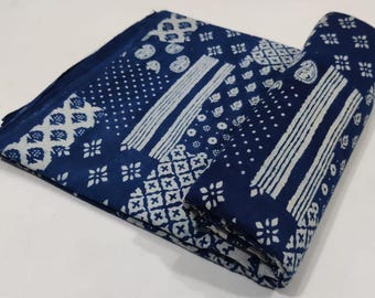 Peut inclure: Tissu bleu indigo avec des motifs blancs. Le tissu est plié et roulé, présentant divers motifs tels que des pois, des rayures et des motifs floraux. L'esthétique générale est un mélange de design traditionnel et contemporain.
