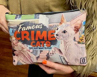 May include: A black zippered pouch with a colorful print featuring a hairless cat, a woman, and the text "Famous Crime Cats They Just Want To Play".