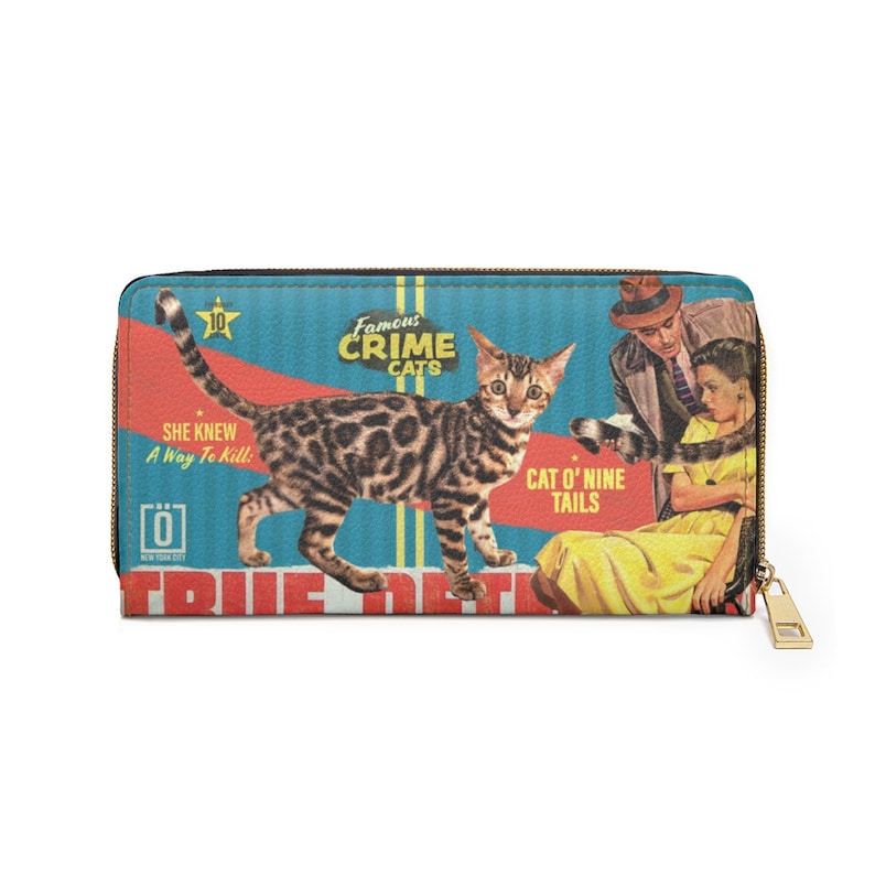 Pu&ograve; includere: Un portafoglio in stile vintage con un'illustrazione colorata di un gatto con il testo "Famous Crime Cats" e "Cat O' Nine Tails". Il portafoglio ha una cerniera dorata.