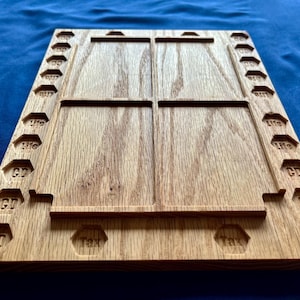 May include: Wooden game board with four rectangular compartments and a row of numbered squares along the sides. The board is made of light brown wood and has the words "Tax" and "GT" engraved on it.